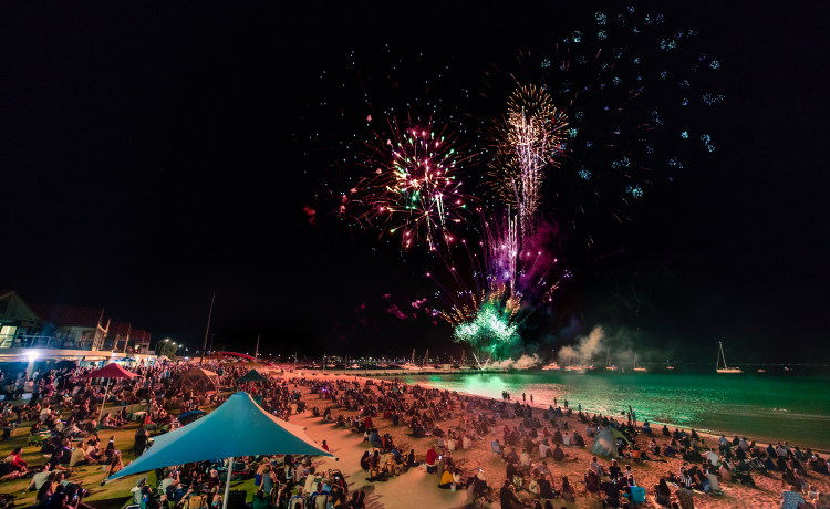 A crowd of people watch colourful fireworks at the Rockingham Foreshore