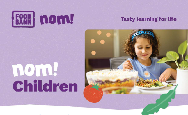 Child sat at a table eating food and smiling. Foodbank nom! logo