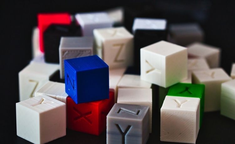 3D printed calibration cubes with letters on faces, multiple colours.