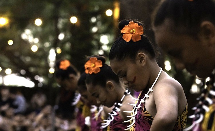 Dancers standing in a line with their head bowed down.