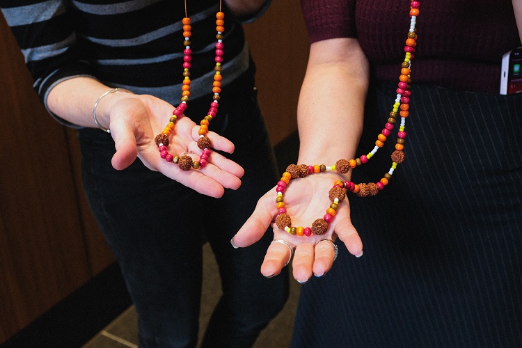 Two people holding their quandong and beaded necklace