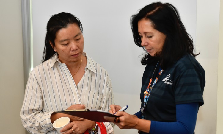 Two ladies talking together and holding a clipboard