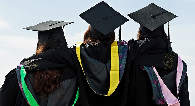 Three people wearing graduation gowns and caps