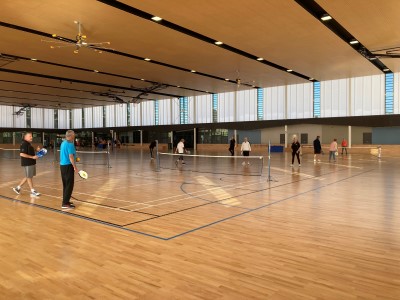 People playing pickleball on indoor courts.