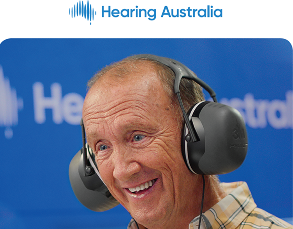 Older man wearing large over the ear headphones and simling