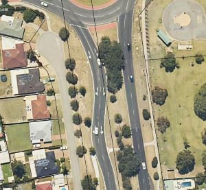Aerial view of curved roads approaching a large roundabout.