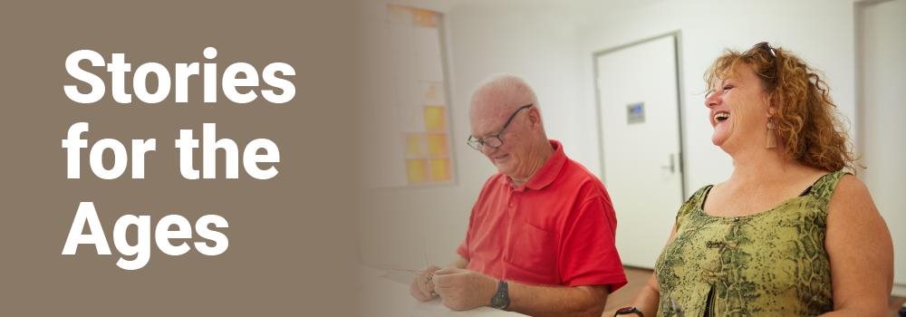 Stories for the Ages image of two older people laughing and smiling while participating in a workshop activity