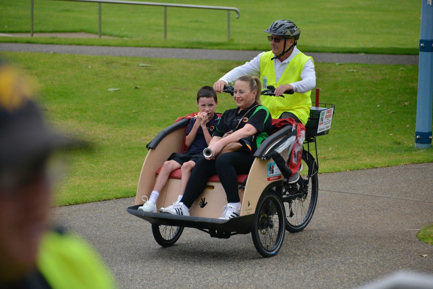 Person giving two people a ride outdoors in a trishaw bicycle.