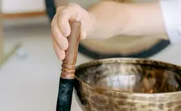 a person holding a wooden stick over a bowl