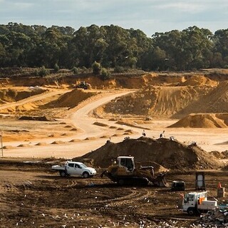a construction site with sand piles and trees