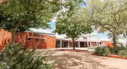 Entrance of Warnbro Community Library with red brick exterior and trees in the courtyard.