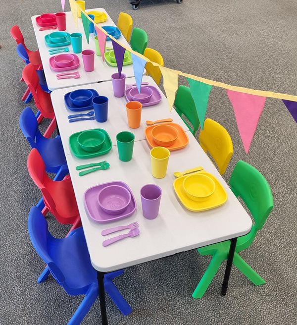displayed party kit available for hire, includes table with plates, utensils and cups, with bunting overhead