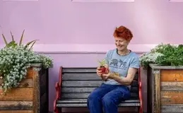 a woman sitting on a bench holding a plant