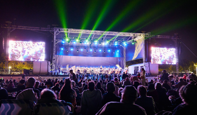 Large crowd and stage lit up with a symphony performing