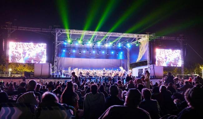 Large crowd and stage lit up with a symphony performing