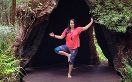 a woman standing on one leg in front of a tree