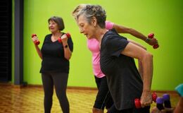 An image of three women using dumb bells to exercise indoors