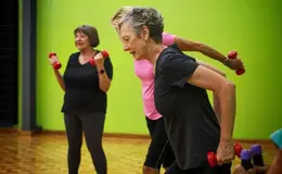 An image of three women using dumb bells to exercise indoors