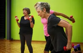 An image of three women using dumb bells to exercise indoors