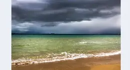 a beach with a body of water and clouds