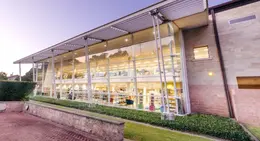 Exterior of Rockingham Library at dusk, showing large glass windows lit from inside.