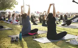 a group of people sitting on mats with their arms up