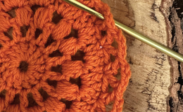 a crochet hook and orange crochet doily