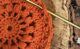 a crochet hook and orange crochet doily