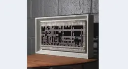 a white framed piece of art on a wood table