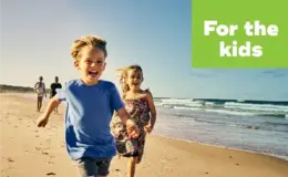 a group of kids running on a beach