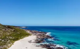 a beach with rocks and blue water