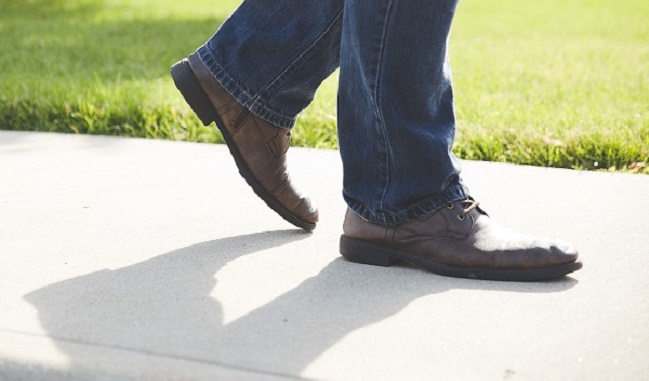 a person's legs walking on a sidewalk