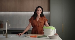 a woman standing in front of a counter with a bucket of vegetables