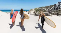 a group of women carrying surfboards on a beach