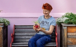 a woman sitting on a bench holding a plant