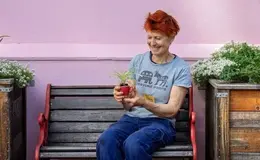 a woman sitting on a bench holding a plant