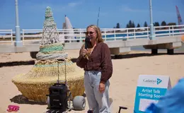 a woman holding a microphone in front of a beach