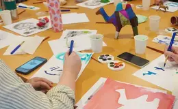 a person drawing on paper on a table