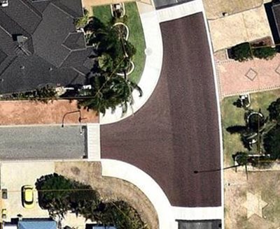 Aerial view of a raised plateau intersection with red-toned paving and white concrete ramps designed to slow vehicle speeds and improve pedestrian safety.