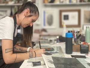 Ashlea etching at a desk in her studio