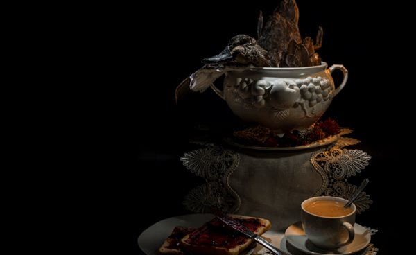 Photo of a table setting in a darkened room with a duck being served.