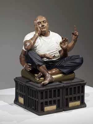 Caved wooden sculpture of a man sitting with many arms