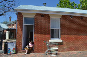 Artist seated in the doorway of a gallery.